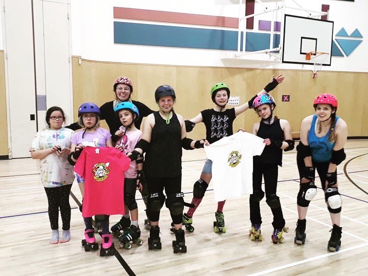 Group of youth on roller blades posing got a photo holding up tee shirts