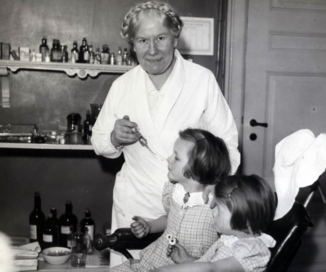 Hedvig giving dental care to my aunt while my mother looks on.