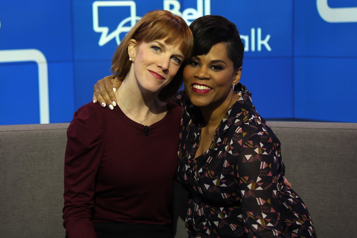 Two women sit on a couch in front of a Bell Let’s Talk logo.