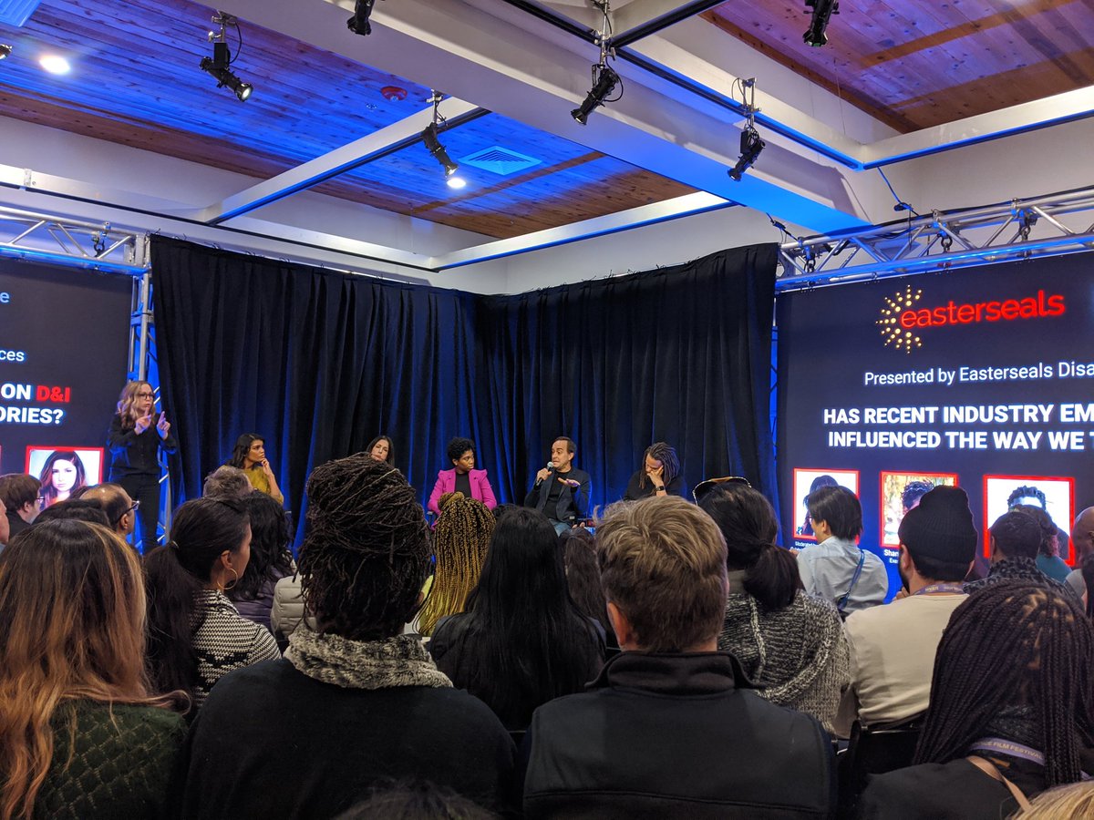 [Image description:. A seated audience listening to the panelists on stage. From left to right: a Sign Language interpreter, Britt 
Stephens, Shoshannah Stern, Shanique Bonelli-Moore, John Travis, and Franklin Leonard.]