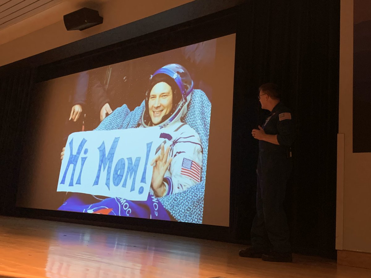 Wheels shows us a photo of him holding a “Hi Mom!” sign for his mother upon return from space.