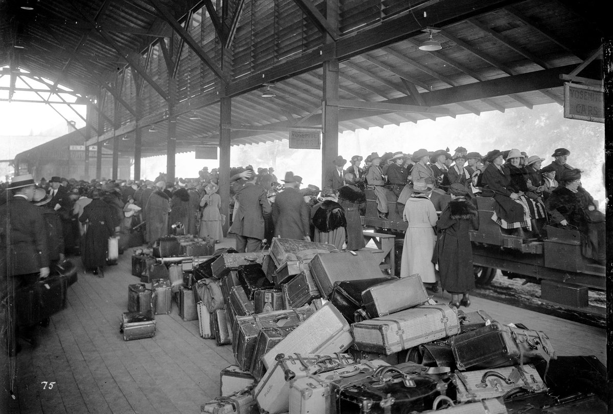 A train platform crowded with luggage and 1910s visitors loaded onto auto stages.