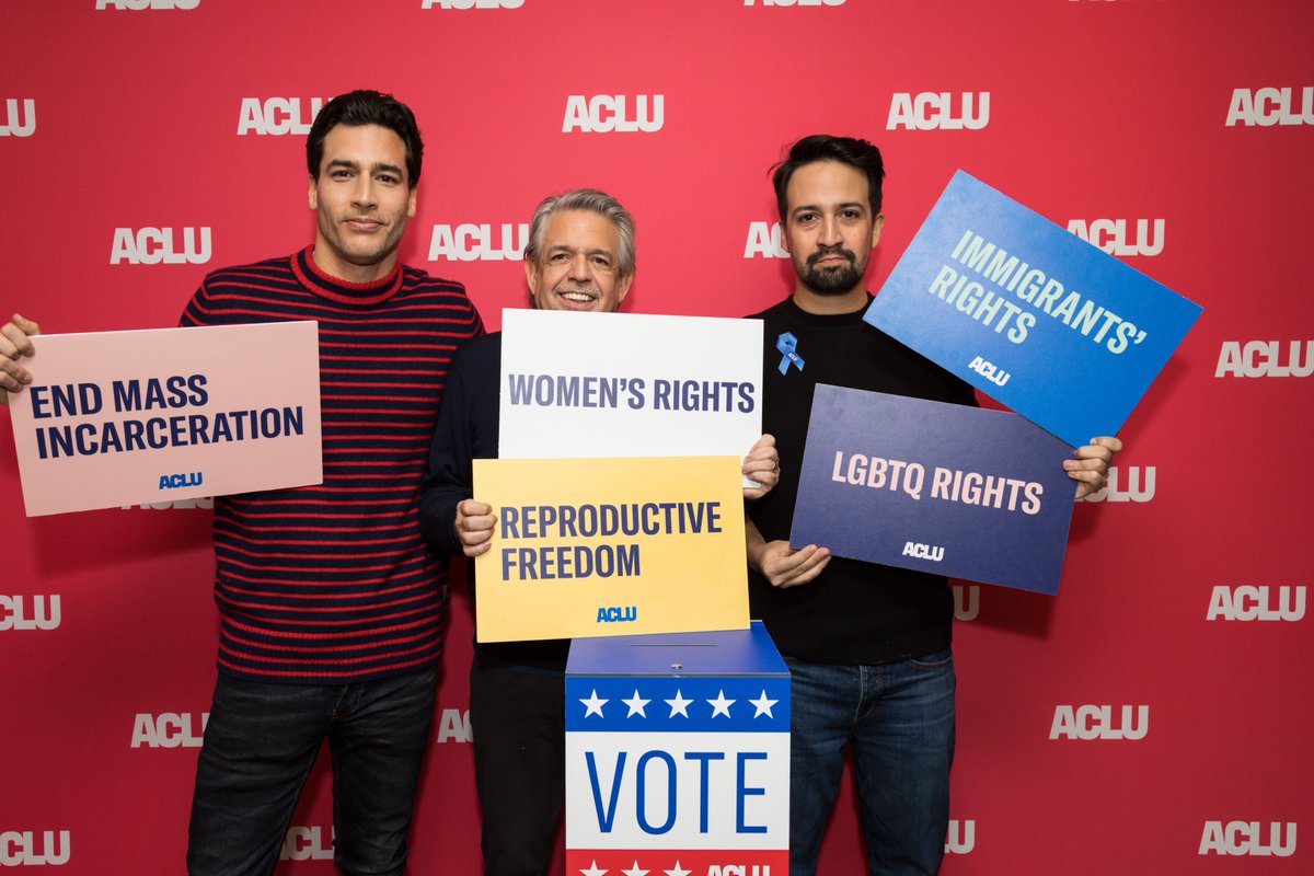 Lin Manuel Miranda, John James, and Luis Miranda holding up signs to support civil rights and civil liberties at the 2020 Sundance Film Festival.