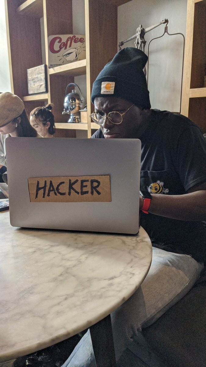 Photo of a MacBook Pro laptop with a piece of brown cardboard reading HACKER taped to it.