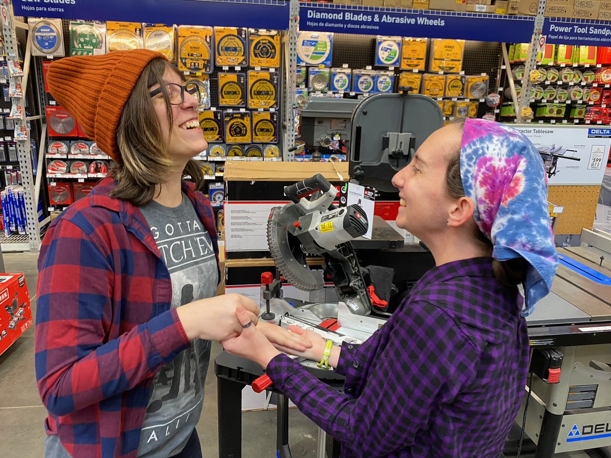 Holding hands in front of the miter saw display at the hardware store