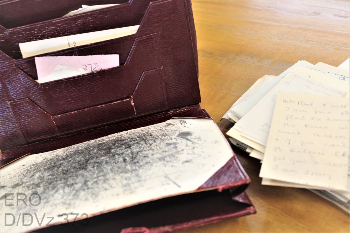 Dark red Leather writing case with card blotter covered in ink. Papers peeking out of pockets and a pile of letters next to it