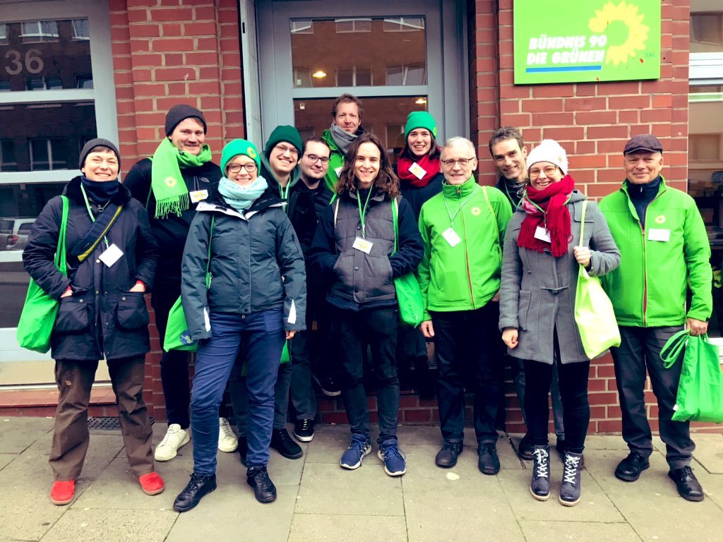 12 Menschen stehen vor der Kreisgeschäftsstelle. Einige davon mit grünen Taschen, Mützen, Jacken oder Schals.