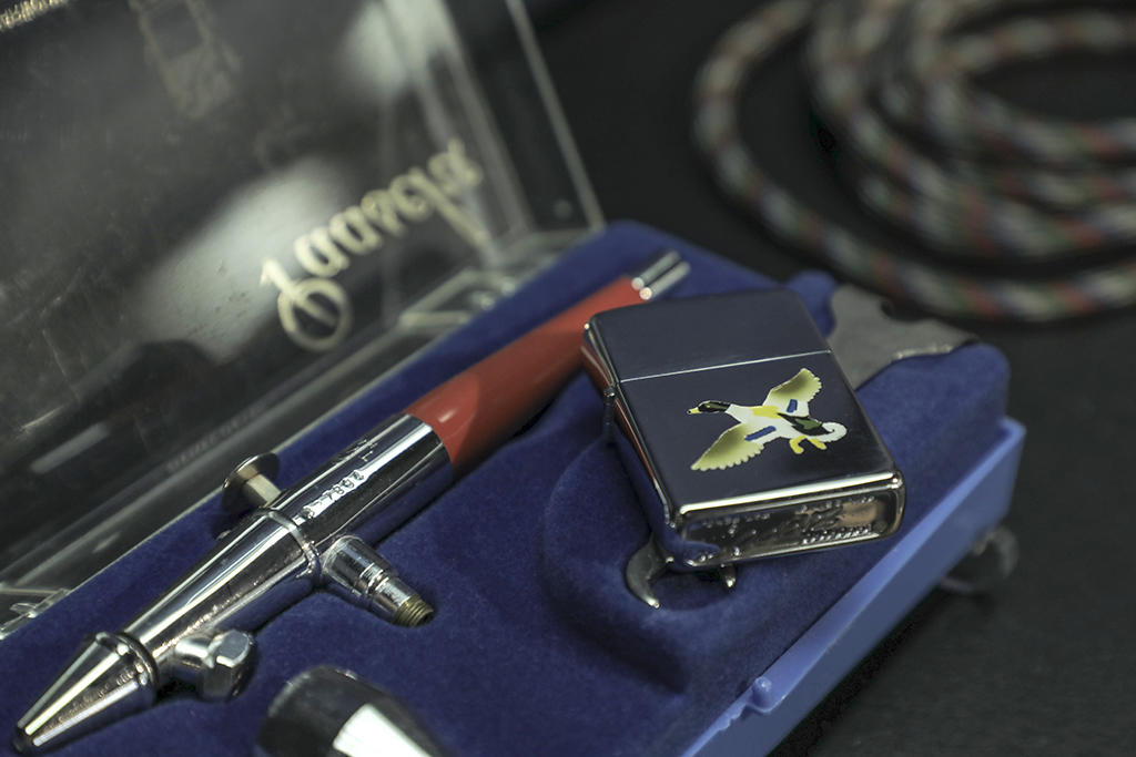 An original Town and Country Zippo lighter with a Duck design lies with an airbrushing tool in the Zippo/Case Museum.