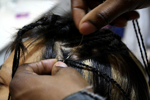 An up close picture of the scalp with braids being sewn in