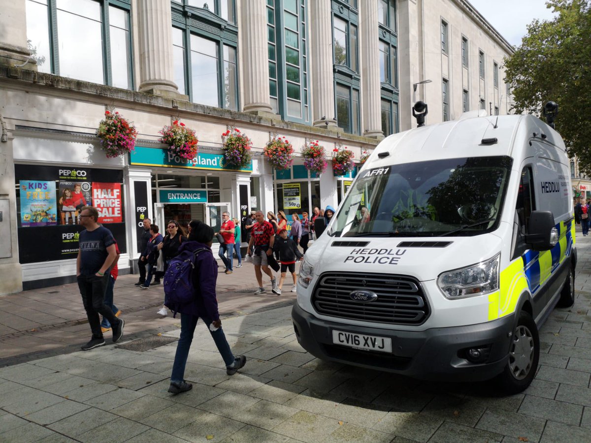 The images shows a South Wales Police facial recognition van in Cardiff. A crowd of people, including children, are walking by the cameras.