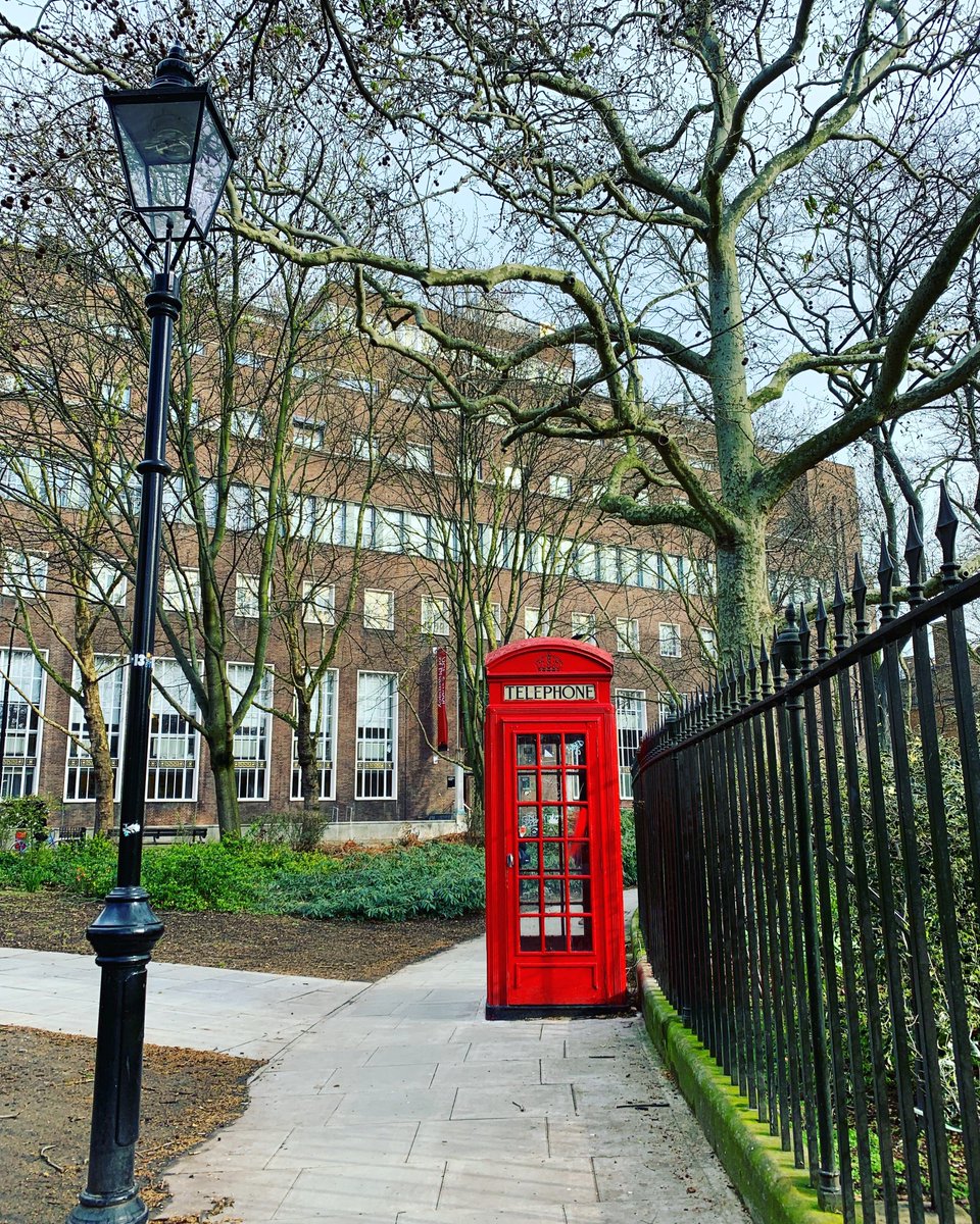 The front entrance of the School of Pharmacy. There is a bright, red phonebox in the foreground. 