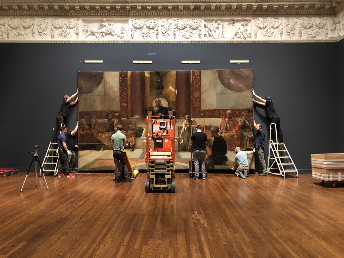 6 museum staff hang the painting Emperor Justinian on a gallery wall