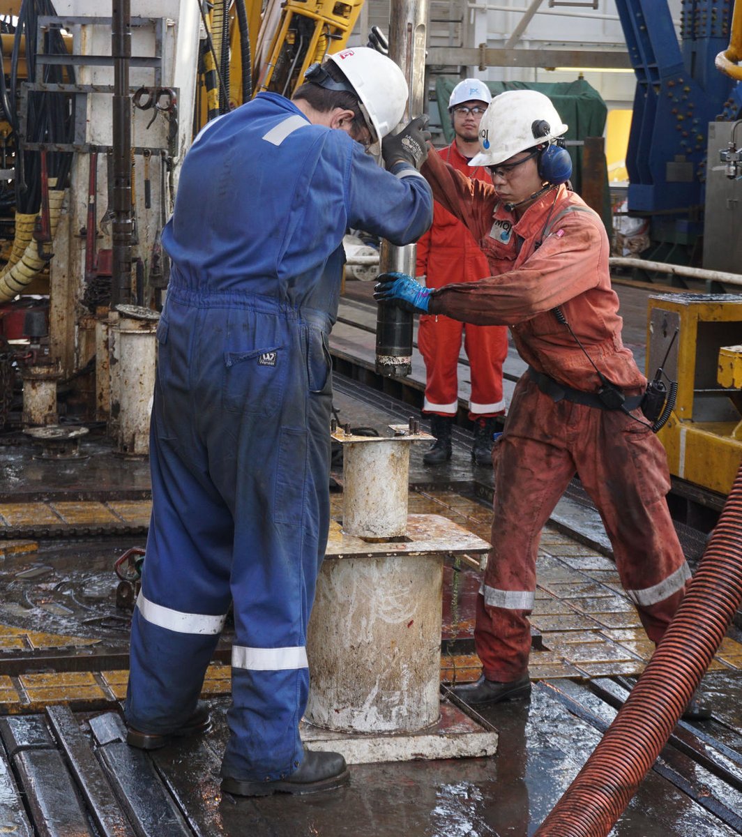 Image shows scientists in hard hats collecting seafloor materials with gas hydrate samples