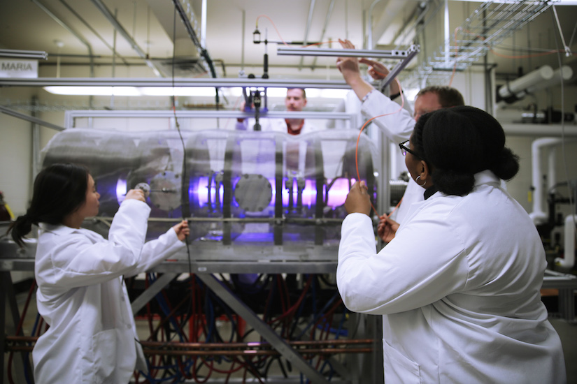 Graduate students Kelly Garcia, Erik Flom, Aysia Demby and Professor Oliver Schmitz work on a plasma experiment in Schmitz’s lab.