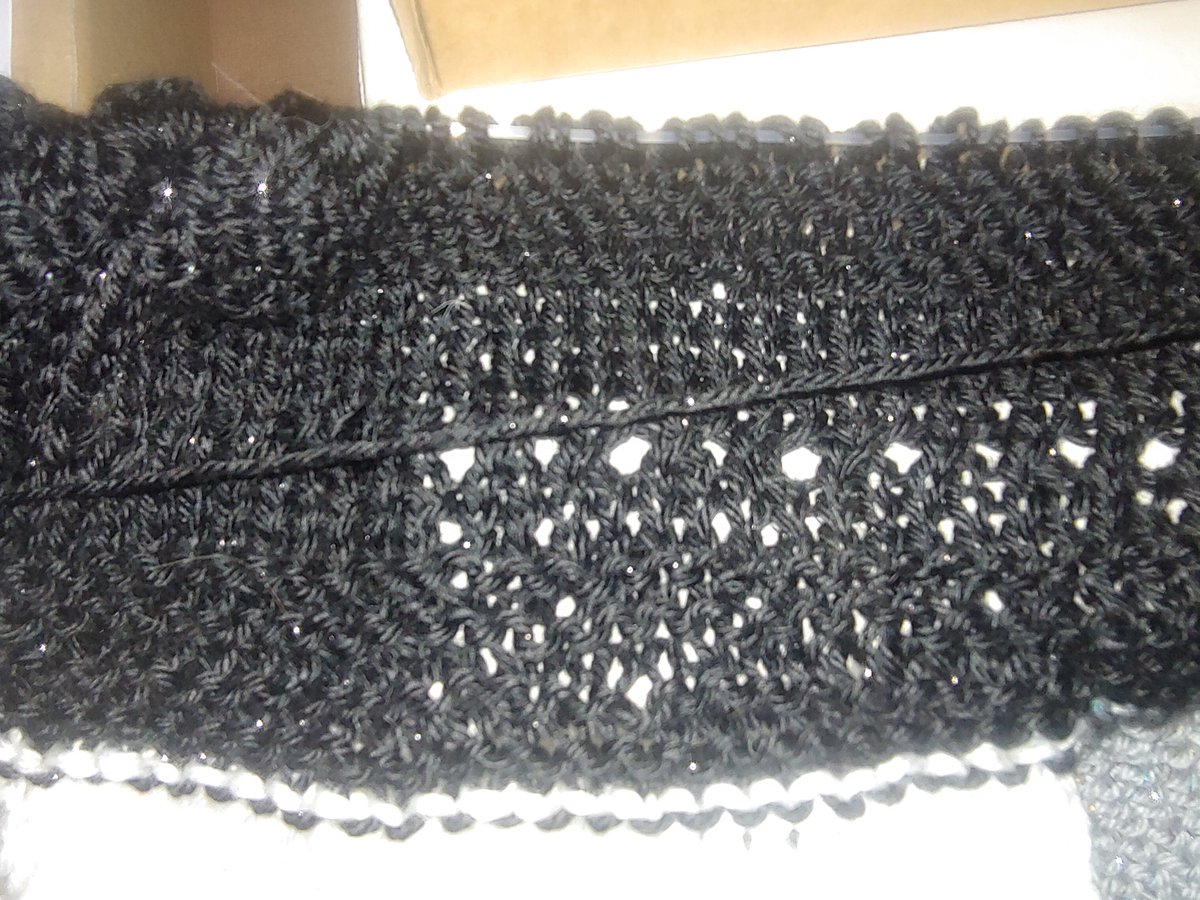 Closeup of a few rows of knitting in black sparkly yarn.