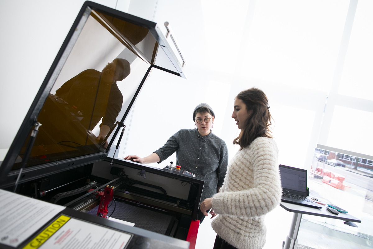 Two students work at a laser cutter