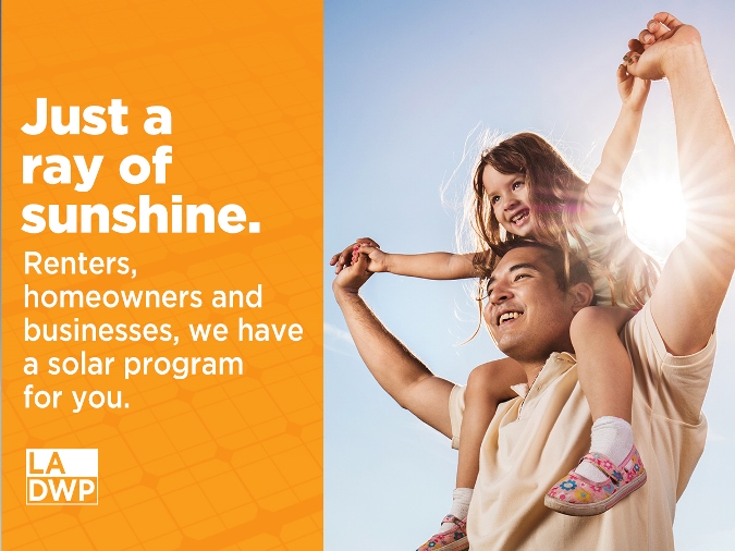 Young girl sitting on the shoulders of a man with sun in the background