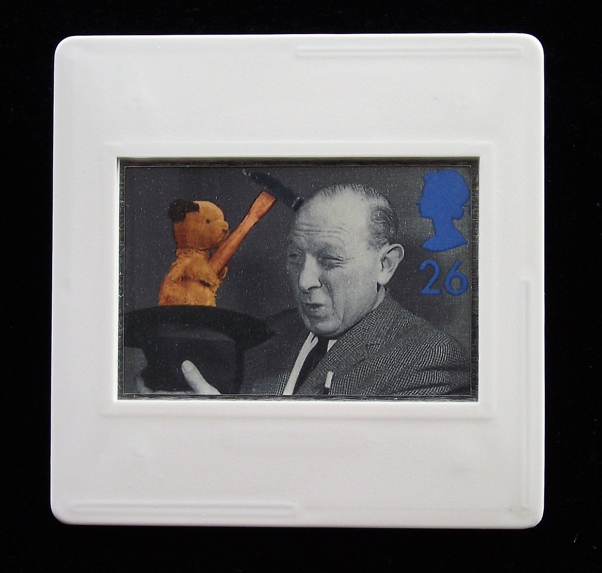 The image is on a Royal Mail postage stamp and shows the black and white photo of the puppeteer, Harry Corbett. He is holding a hat in his right hand where Sooty, the bear glove puppet is seen holding a hammer and tapping Harry on the head. Harry's eyes are partially shut and his mouth looks as though he's saying 'ooo' as he receives the tap on the head.The photograph is black and white except for hammer and bear.