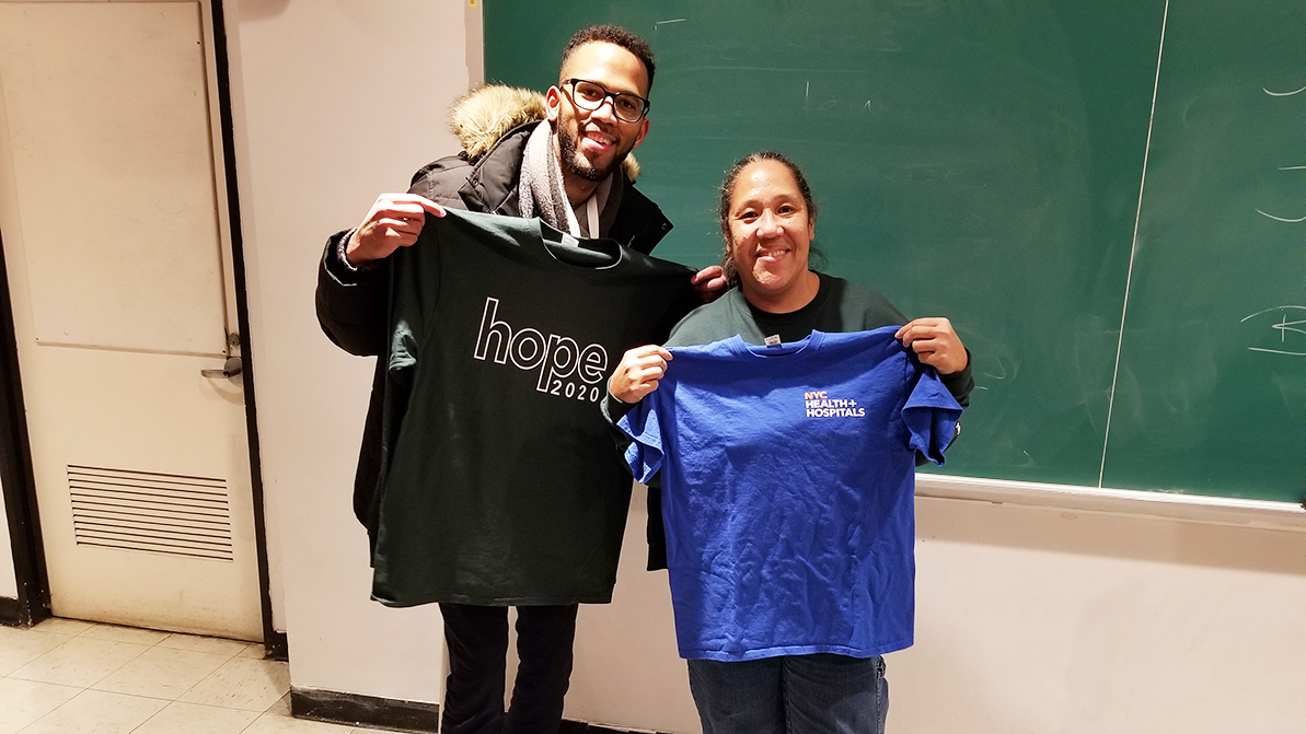 Two people holding up T-shirts.