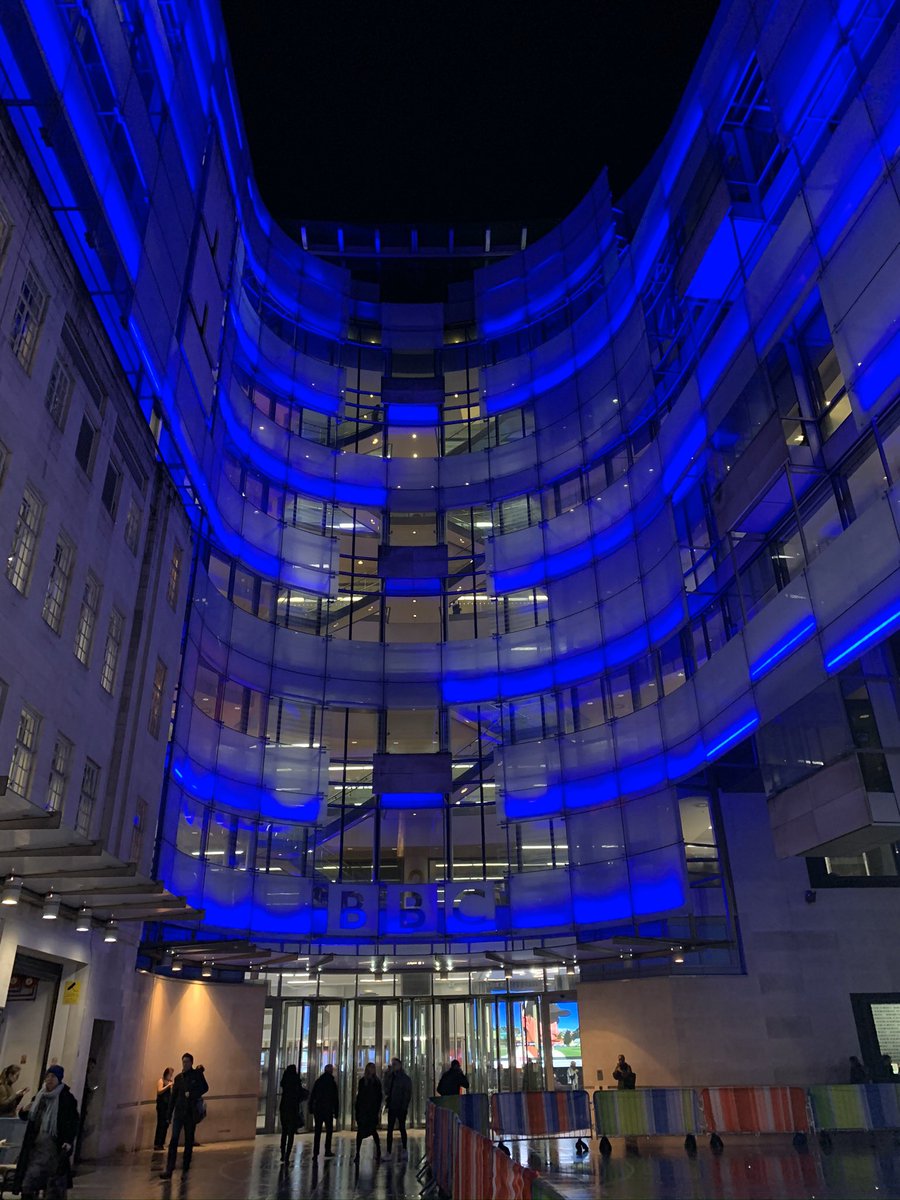 The BBC building in London. Tall and neon blue. A stunning building like a modern amphitheatre.