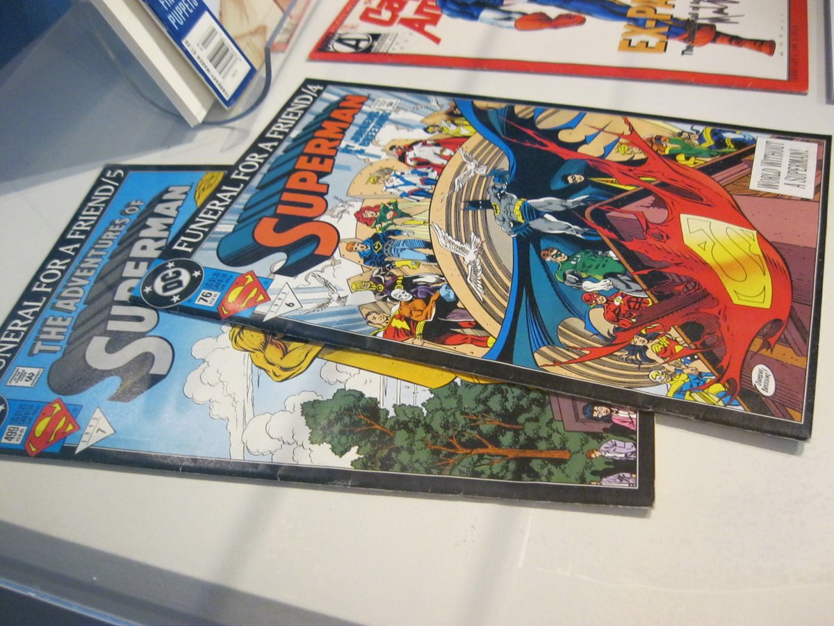 Photo of vintage comic books "Superman: Funeral for a Friend/4" and "The Adventures of Superman: Funeral for a Friend/5" in an exhibit case on display in our museum. 