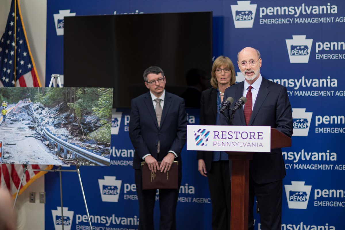 Governor Tom Wolf speaks behind podium with microphones. DCNR Secretary Cindy Adams Dunn and Pennsylvania DEP Secretary Patrick McDonnell stand behind him and look on.