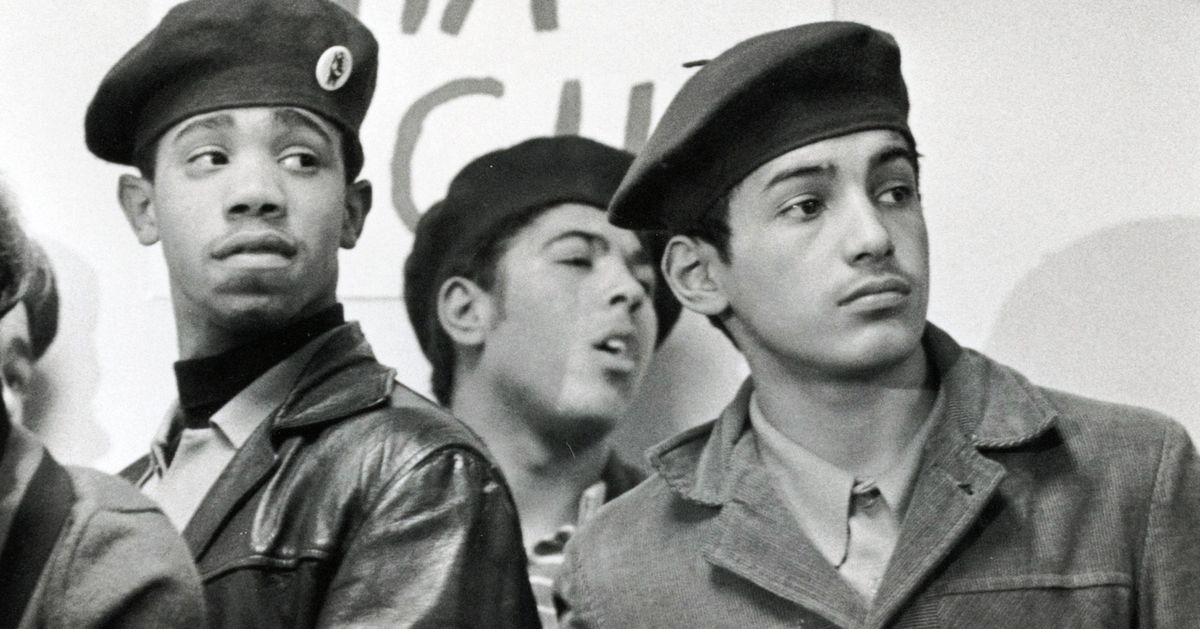 Three young Latino men wear black berets.