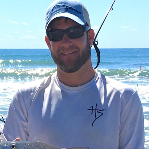 David holding a fish in front of the ocean