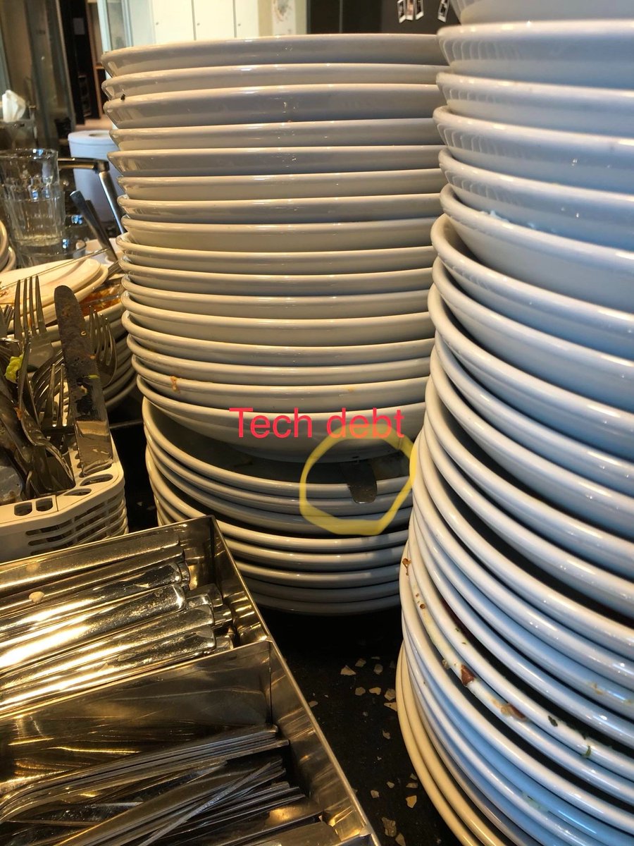 Tall stack of plates with cutlery sticking out halfway down the stack