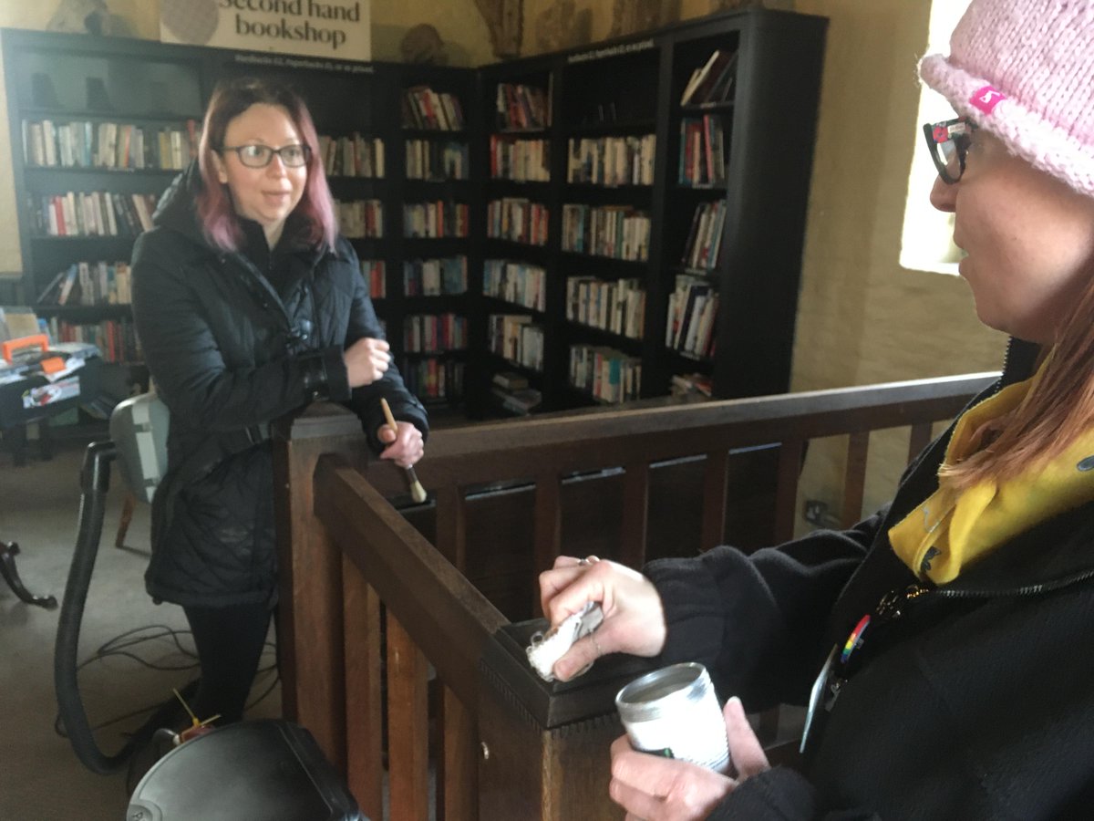 Two volunteers talking about the waxing and cleaning of stair bannisters