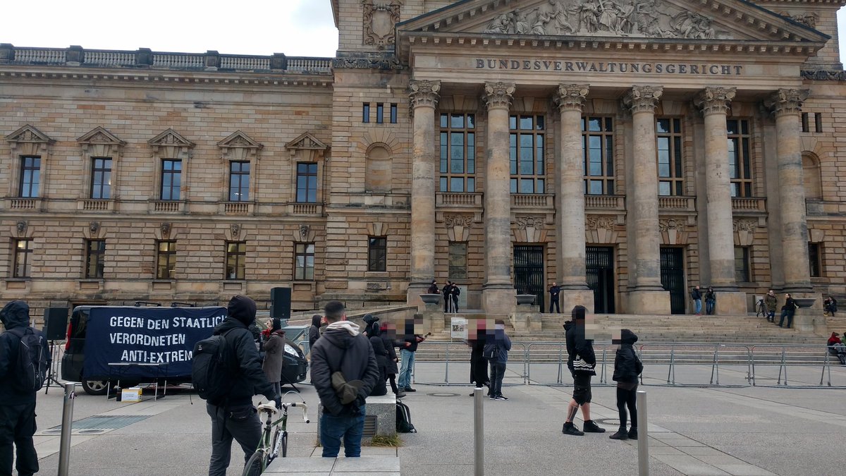 Protest gegen das linksunten-Verbot steht vor dem riesigen Bundesverwaltungsgericht in Leipzig. Das Gebäude ist mit Gittern abgesperrt, davor steht ein Lautsprecherwagen der Kundgebung.
