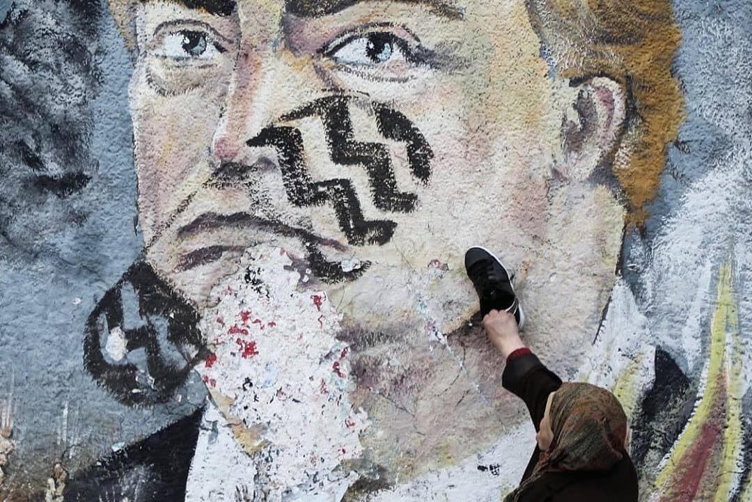 moneeb_saada's tweet photo. A Palestinian woman places a shoe a graffiti painted by Palestinians protesters showing US President Donald Trump with a footprint on his face in a street of Gaza City. https://t.co/P0mr6f7OJJ