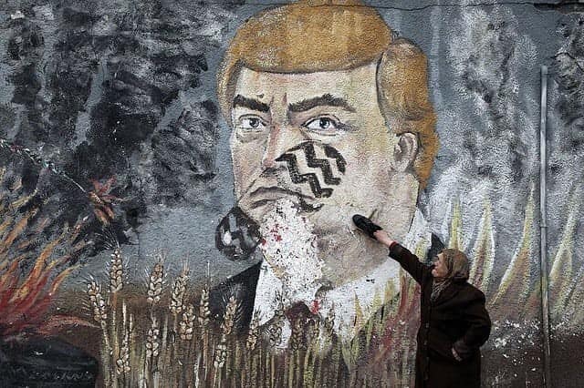 moneeb_saada's tweet photo. A Palestinian woman places a shoe a graffiti painted by Palestinians protesters showing US President Donald Trump with a footprint on his face in a street of Gaza City. https://t.co/P0mr6f7OJJ