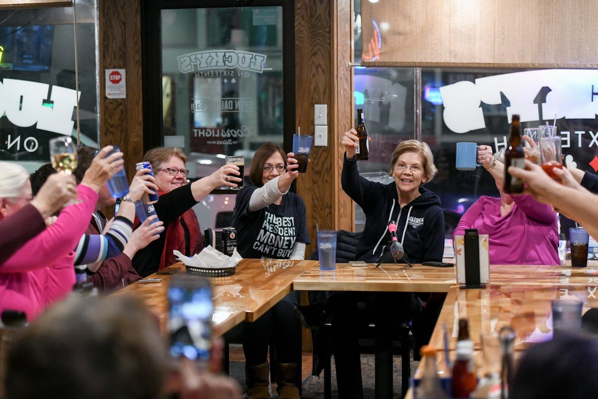 Elizabeth sitting at a table with campaign volunteers. Everyone holds up a drink to 'cheers.'