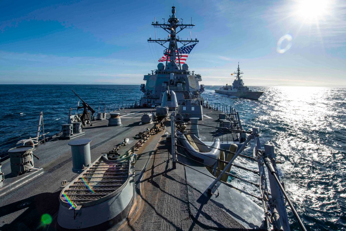 A U.S. Navy ship, in the foreground, travels next to a Spanish frigate during a routine passing exercise in the Atlantic Ocean.