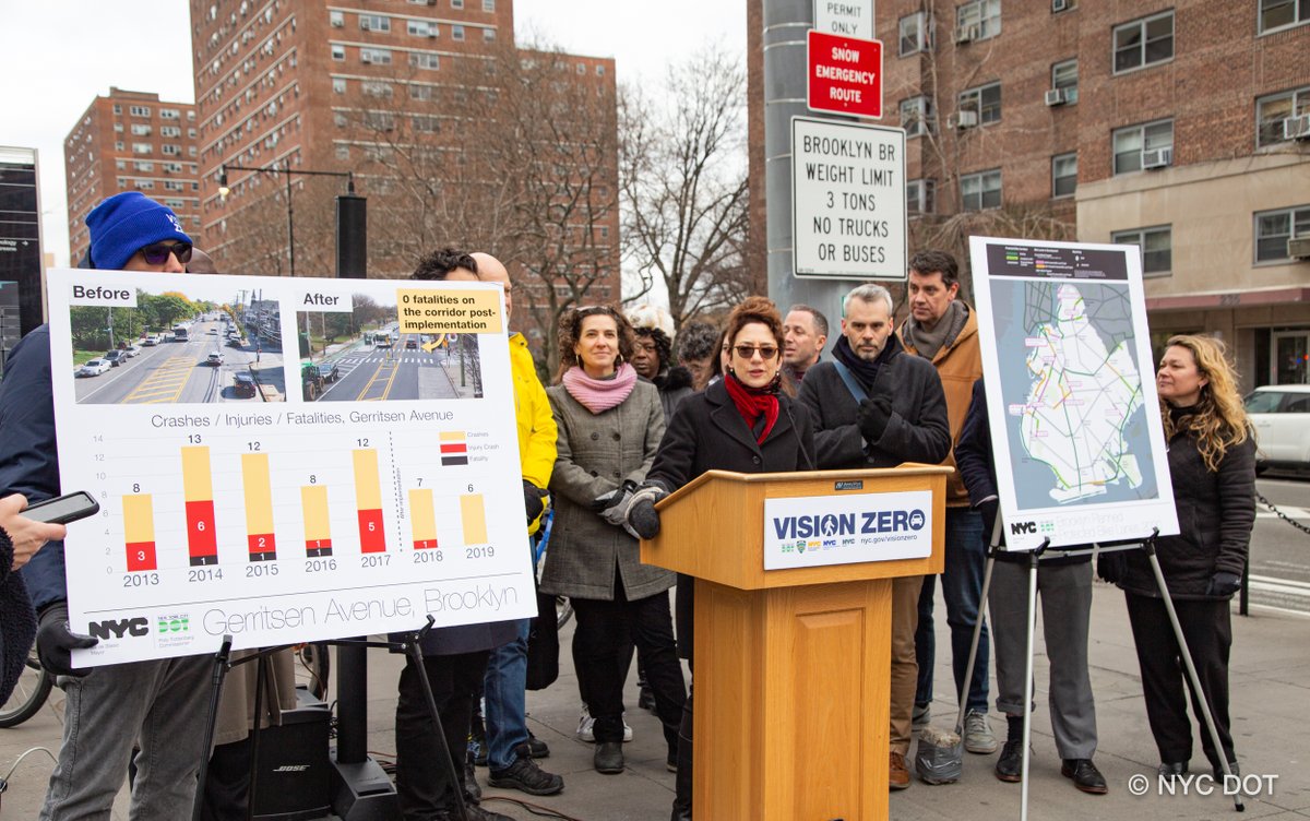 Commissioner Trottenberg speaks at a podium, surrounded by people. A board on one side of her says Gerritsen Ave, Brooklyn showing crashes going down after safety improvements. A board on the other side shows planned protected bike lanes in brooklyn.