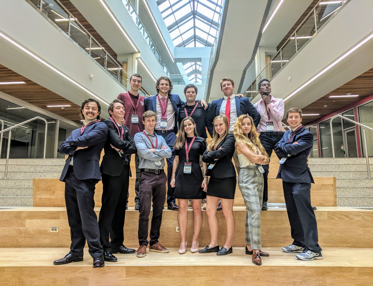 Group of undergraduate standing in power poses on stairs indoors. Business professional attire, determined looks, power pose