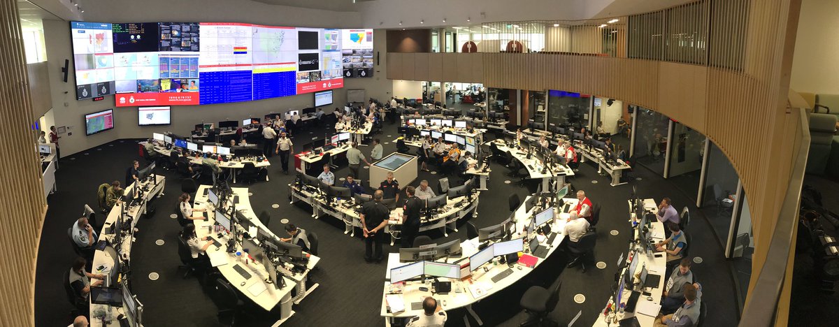 Dozens of people working in a large room filled with computers and monitors