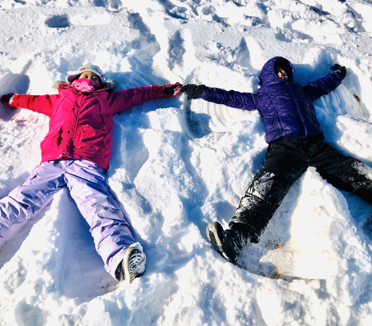 Image of two students laying in the snow doing snow angels.