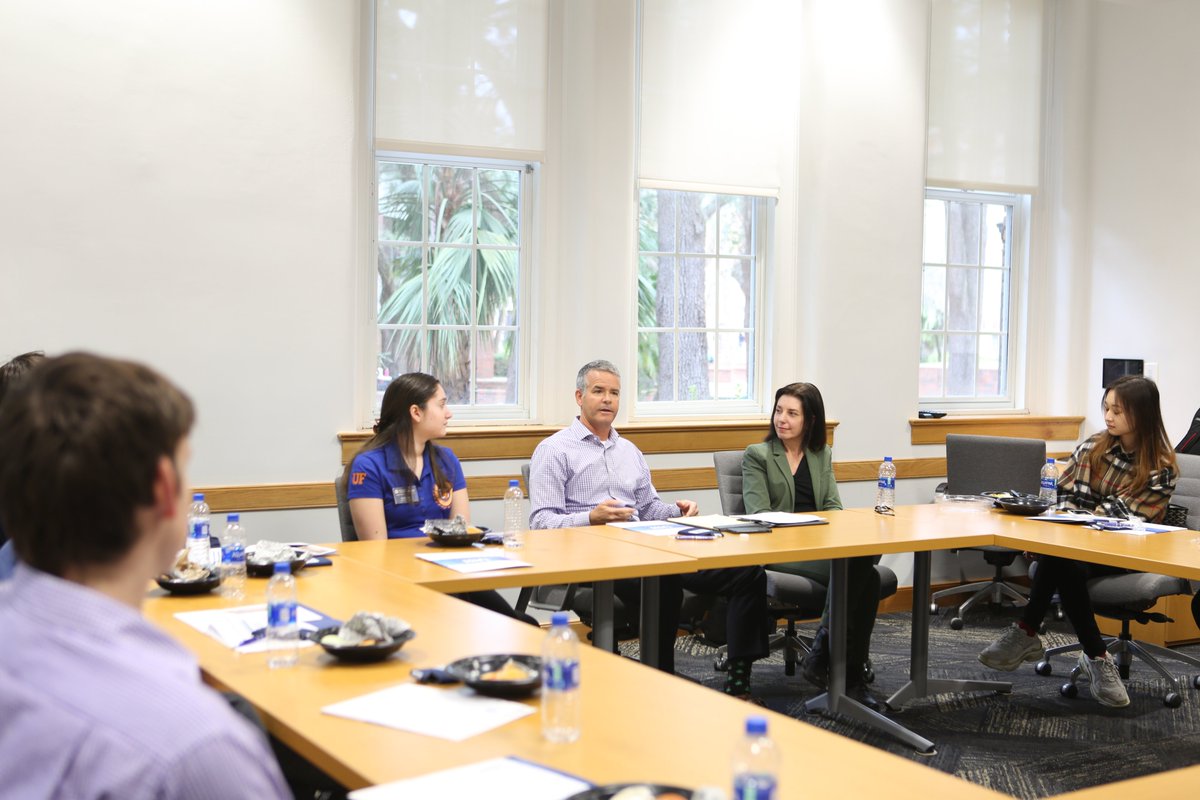 Man sitting at a table speaking with other seated people 
