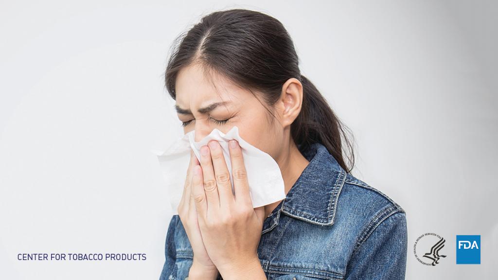 A woman sneezing into a tissue 