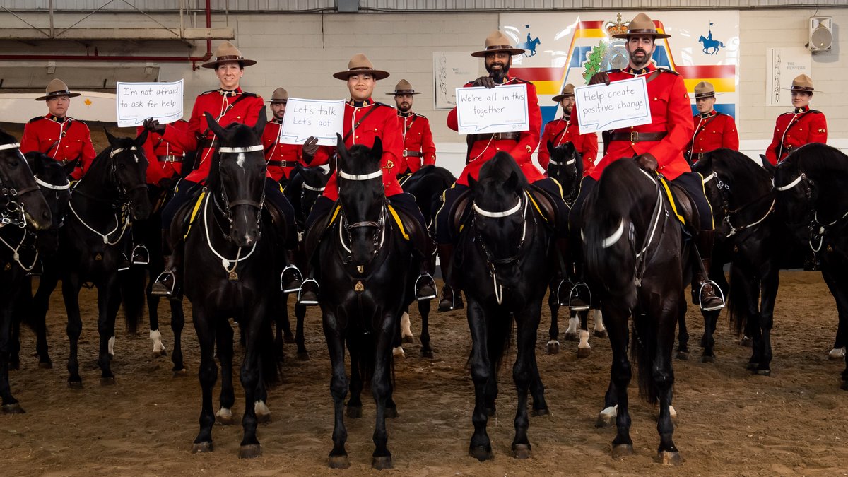 Members of the RCMP's Musical Ride holding Bell Let's Talk signs with hand-written messages, such as "Let's talk, let's act" and "Help create positive change."