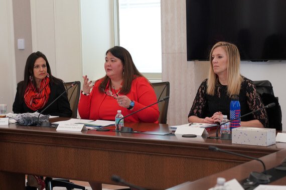 Three women sit together at a conference table discussing important issues.