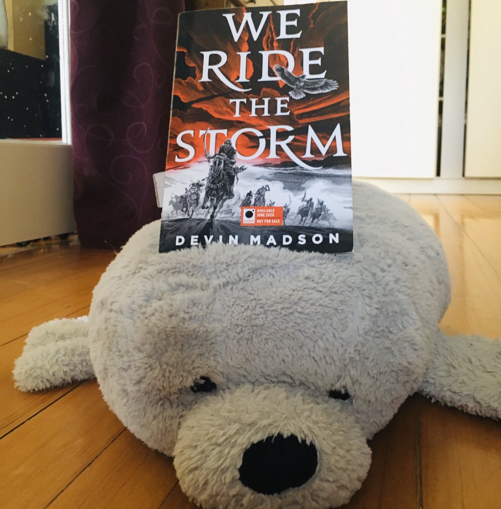 An advanced reading copy of the book We Ride the Storm riding on the back of a large plush seal