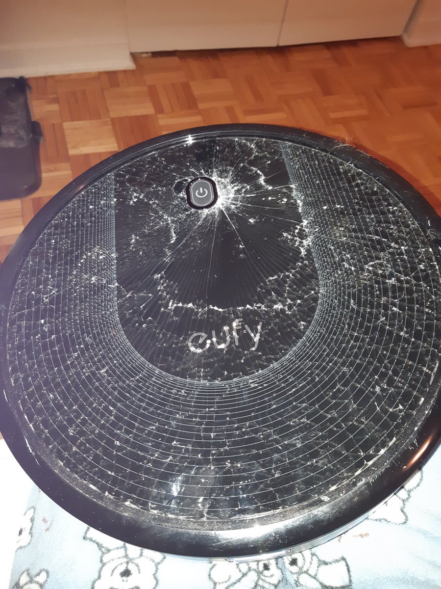 Eufy round black robot vaccuum with the top all busted and cracked