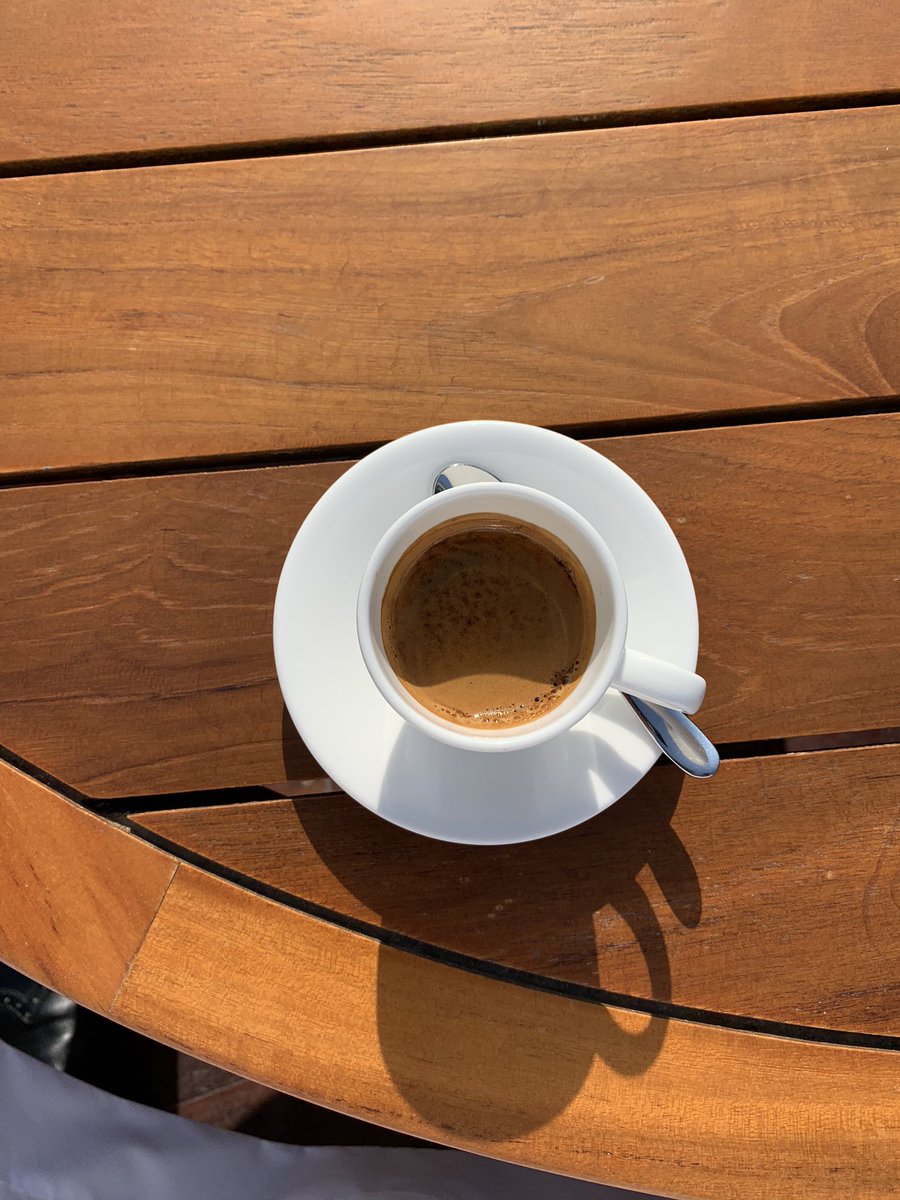 صورة لفنجان قهوة اسبريسو ورغوته الذهبية لونها يماثل لون الطاولة الخشب التي وضع عليها الفنجان