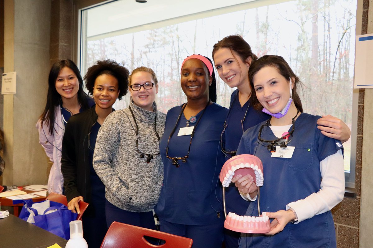 A group of UMMC dental students stand together with a model of teeth.