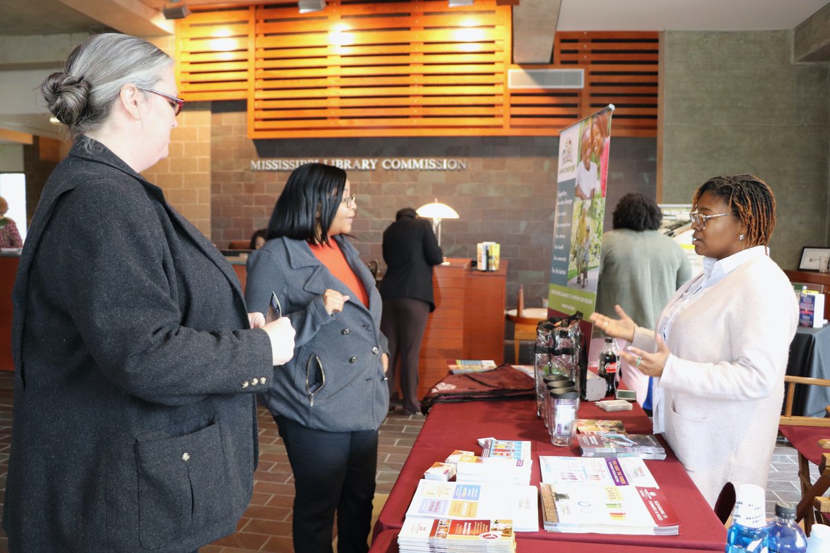 A representative from Mississippi State University Extension talks to two women at a booth.