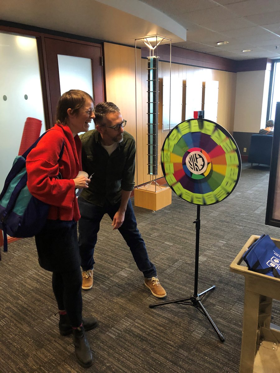 Two Department of Neighborhoods employees spin a prize wheel.
