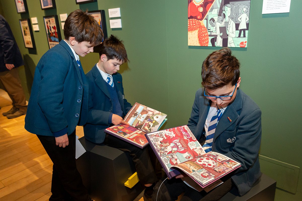 Three school children reading comics in the Parasites exhibition